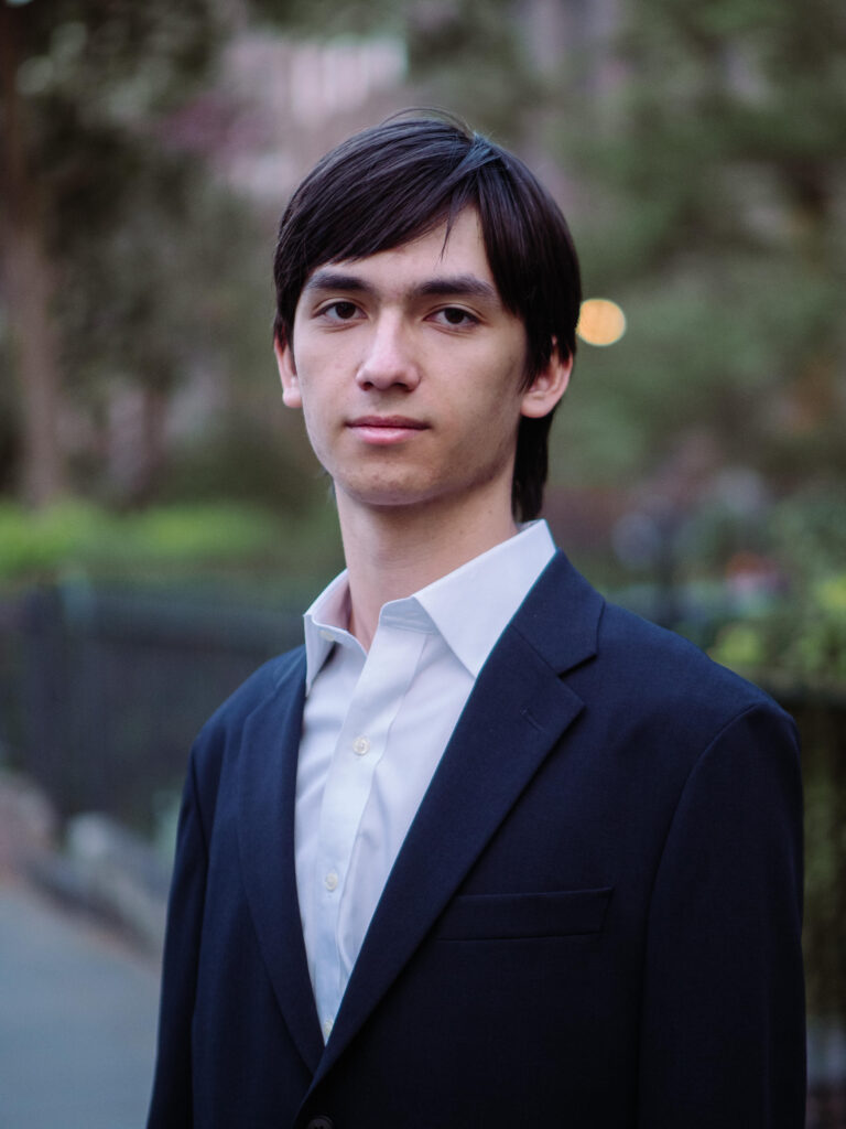 Photo of Evan Lum standing with sidewalk background.